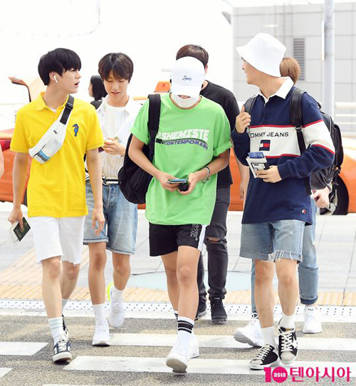 Các chàng trai của NCT rủ nhau mặc quần ngắn, áo phông màu sắc khi ra sân bay.